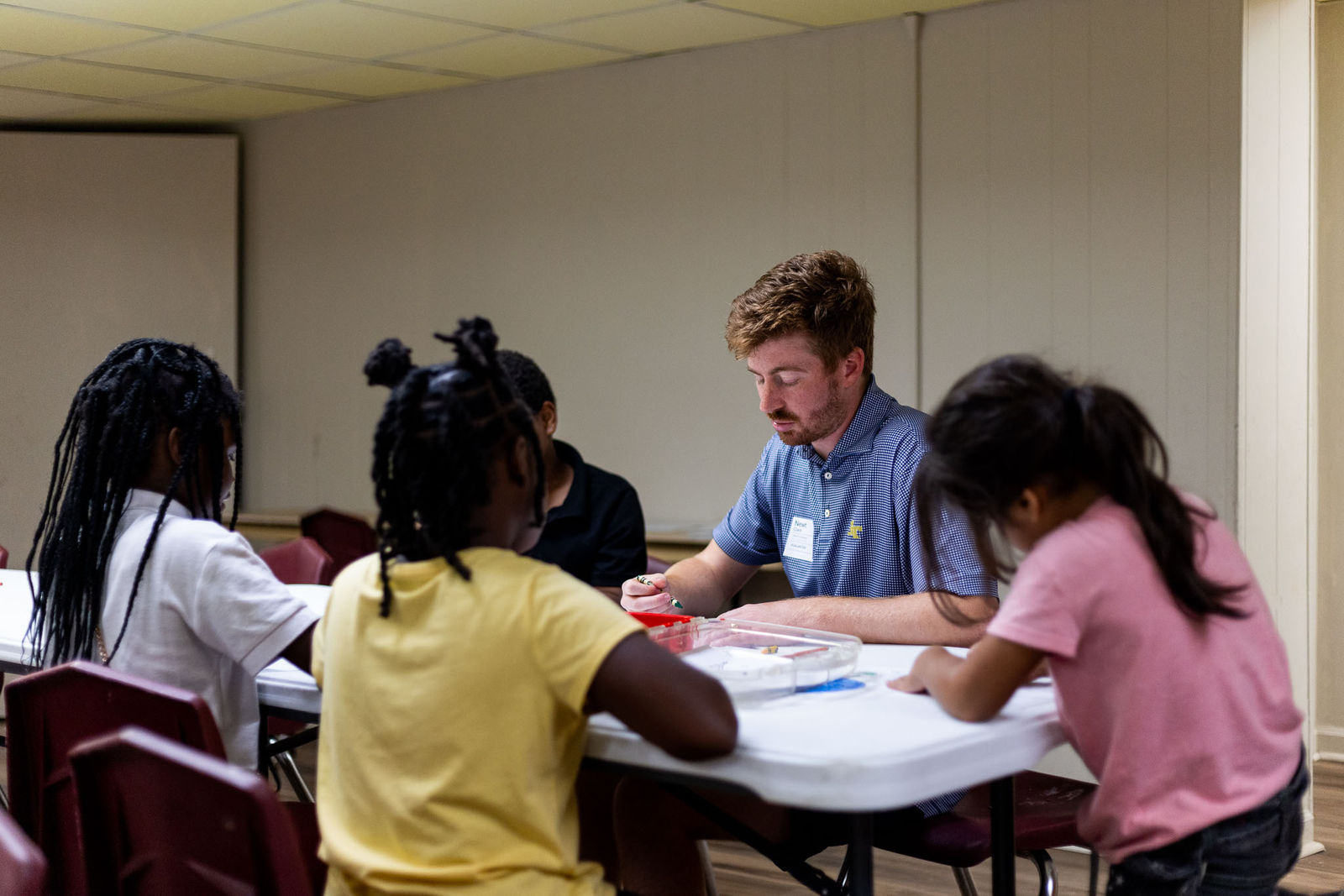 Volunteers working with children around tables at ThriveKids